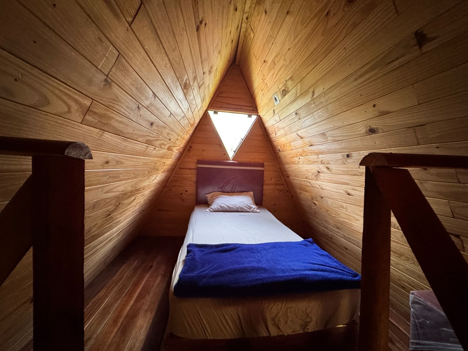Cama individual en el altillo de la cabaña alta, bajo el techo a dos aguas