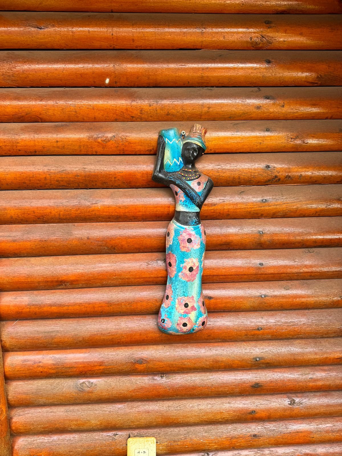 Figura de cerámica con cántaro sobre la pared de madera