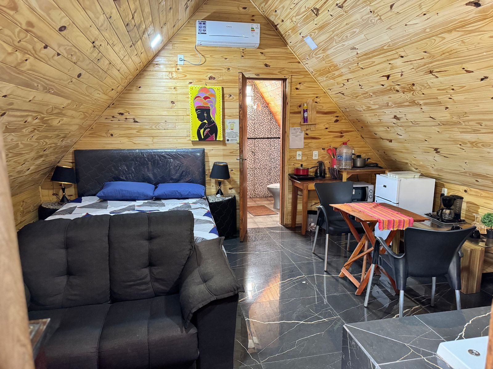 Interior de la cabaña alta: cama matrimonial, estar y kitchenette